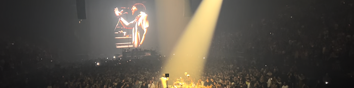 a photo of KTM performing, surrounded by a sea of people, with a projection of him up on a giant screen